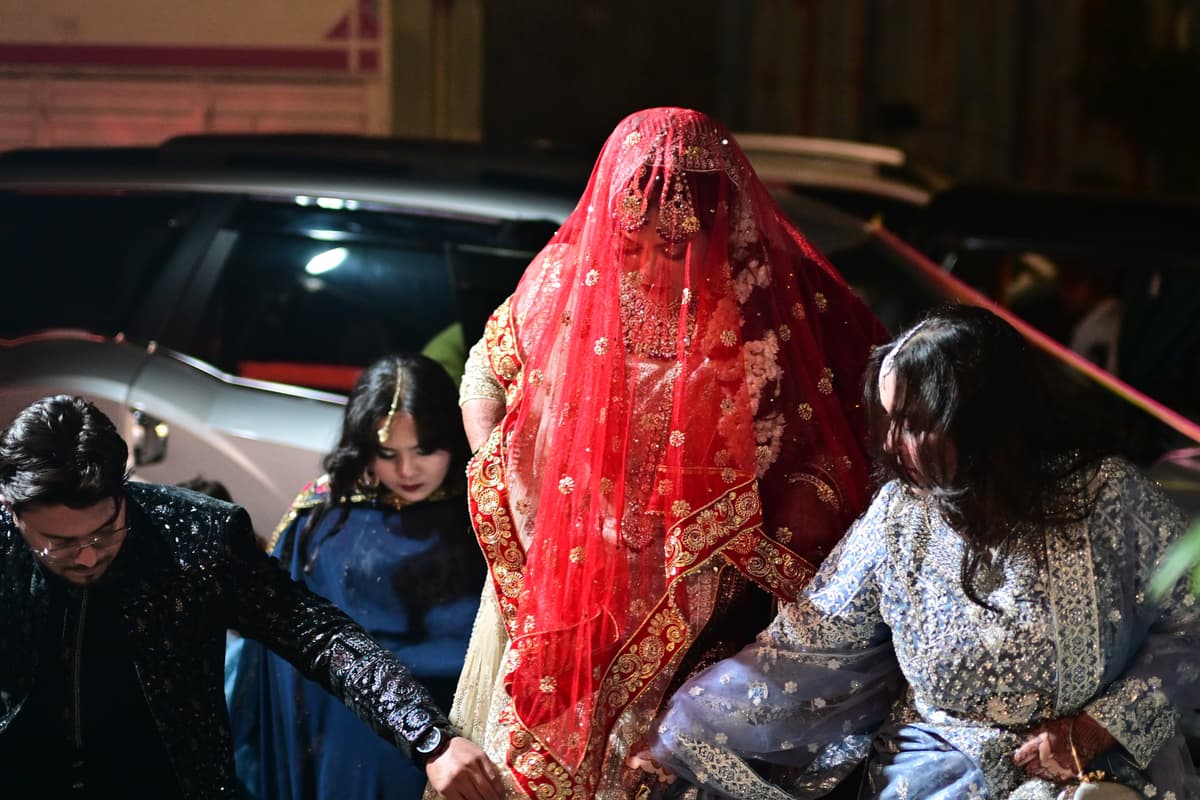 Wedding Photography - Bride entring into wedding hall, her head cover with beautiful red veil
